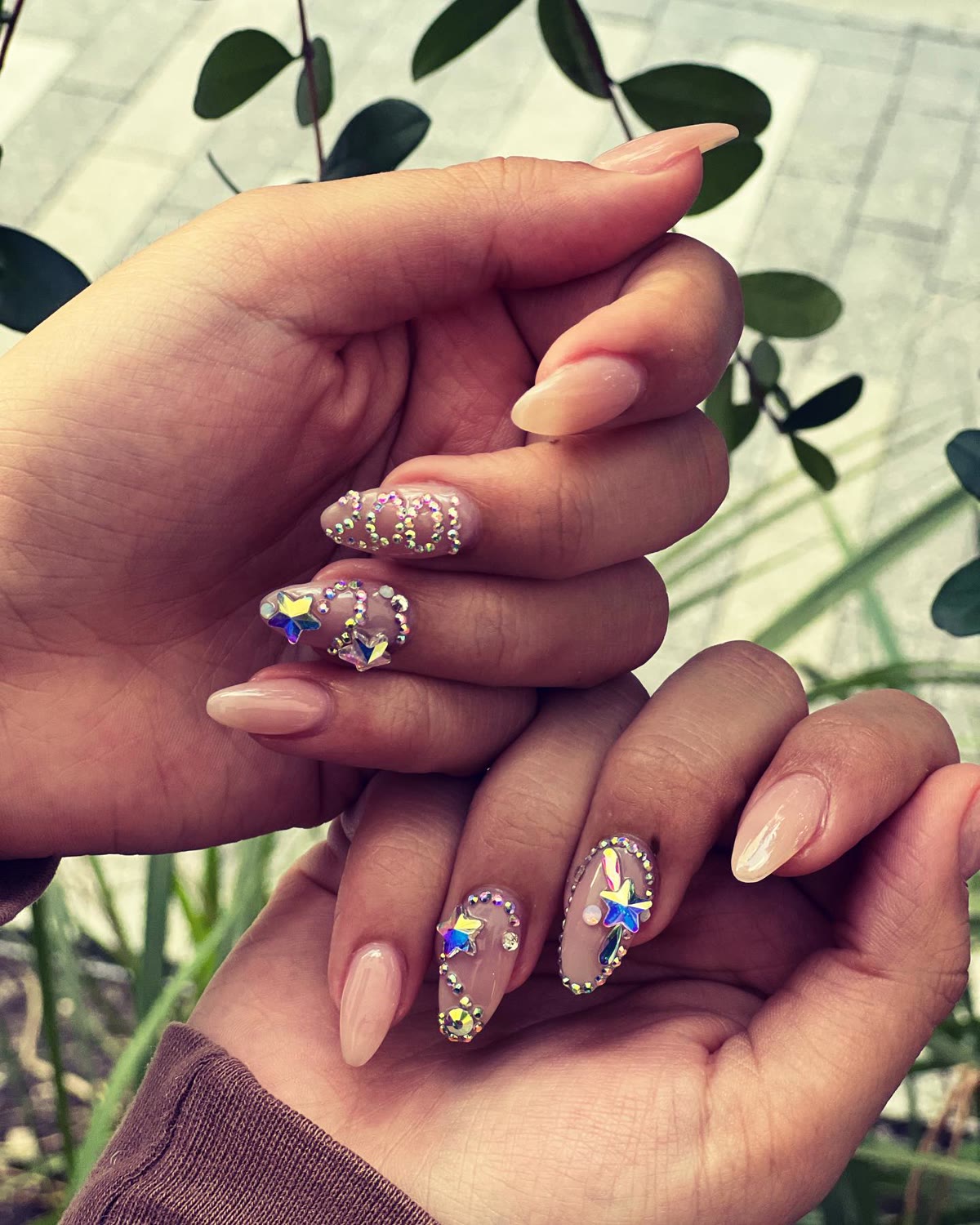 Nude almond nails with gold glitter, crystals and jewel accents.